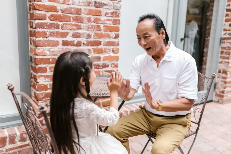 A grandfather playing a clapping game with his granddaughter